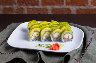 sushi roll avocado topping white plate brick wall