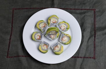 sushi roll crab meat and avocado on a white plate and grey cloth
