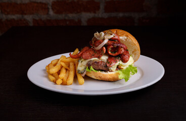 Bacon burger on a white plate with fries