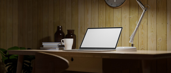 Dark home working room with opened laptop, table lamp, work at night concept