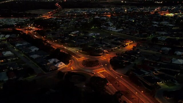 Aerial Hylerlapse circling around a roundabout on the road at night with traffic in Perth Western Australia
