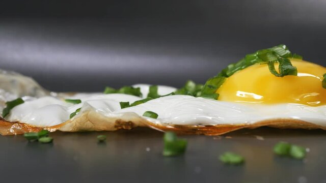 Extreme close-up in a pan fried egg with green onions and fried protein. Dolly shooting