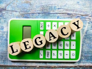 Business concept.Text LEGACY writing on block cylinder with calculator on a wooden background.