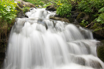 Beautiful waterfall in the mountains. Silky water flows down the rocks. Long exposure.