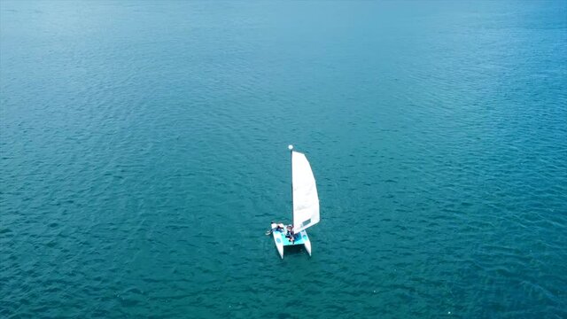 A aerial view of a small sailboat in the blue of the Caribbean waters on a sunny day.
