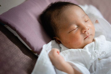 Asian newborn sleeping on bed. New family, protection, relaxation and relationship concepts.
