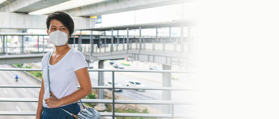 Fototapeta premium Asian woman wearing N95 face mask standing on sky walk during go to work. social distancing, coronavirus, quarantine or new normal concepts