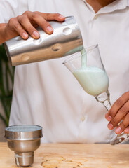 A man pouring a drink into a glass goblet