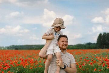 Happy father's day. Little boy and father are playing in a beautiful field of red poppies.