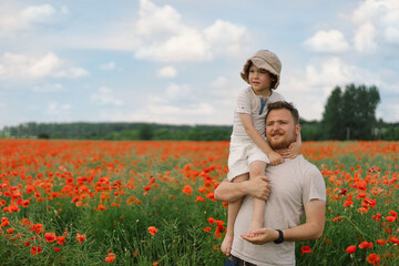 Happy father's day. Little boy and father are playing in a beautiful field of red poppies.