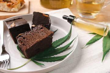 Homemade sweetmeat with marijuana or cannabis leaf on white plate. Alternative medicine concept..