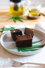 Homemade sweetmeat with marijuana or cannabis leaf on white plate. Alternative medicine concept..