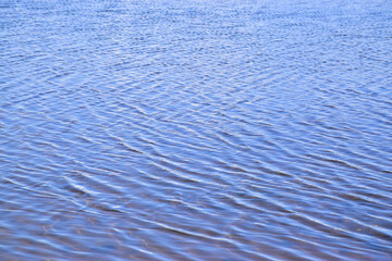 Day shot of a horizontal abstract seascape of dark blue sea with water ripple wave and reflection pattern background. Natural texture view with copy space for texting and designing in holiday concept