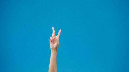 Young woman hand showing thumb up sign with fingers isolated over blue background in studio. Copy space for place a text, message for advertisement. Advertising area, mock up promotional content.