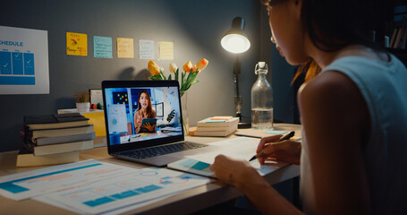 Asia businesswoman using laptop talk to colleagues about plan in video call meeting at living room...
