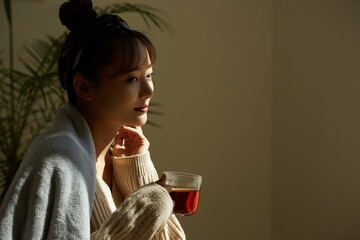 自宅でフルーツティーを飲みながらリラックスする若い女性