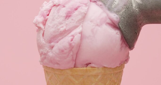 Close-up detail - Hands scoop Ice cream strawberry in waffle cone isolated on pink background, Front view Blank for design.
