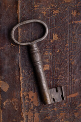 Door key in old metal, on an ancient brown surface.
