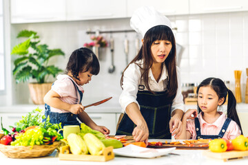 Portrait of enjoy happy love asian family mother and little asian girl daughter child having fun cooking together with fresh vegetable salad and sandwich ingredients on table in kitchen