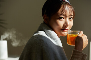 自宅でフルーツティーを飲みながらリラックスする若い女性