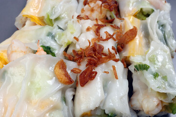 Chinse steamed rice noodle roll cheung fun stuffed shrimp prawn chicken vegetable fried onion garnish on dark plate