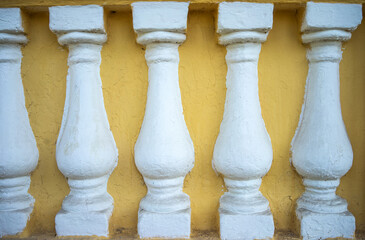 Semicircular columns of white color on the wall of the old building are yellow