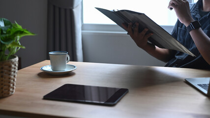 Digital tablet and coffee cup on wooden desk.