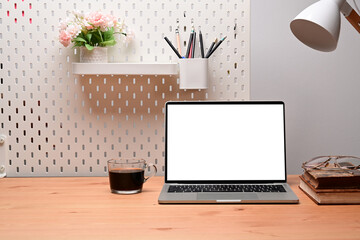 Fototapeta premium Front view laptop computer, coffee cup and books on wooden desk.