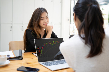 Two businesswoman working together with laptop computer in modern office.