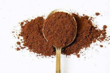 a spoonful of ground coffee on a white background close-up
