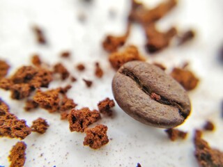 A close up macro picture of a coffee bean with coffee powered in the background