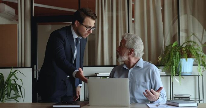 Angry young boss reprimanding shout at older employee, accusing blaming for mistake, unqualified in modern technology, lost important information in laptop, company failure, bad work results concept