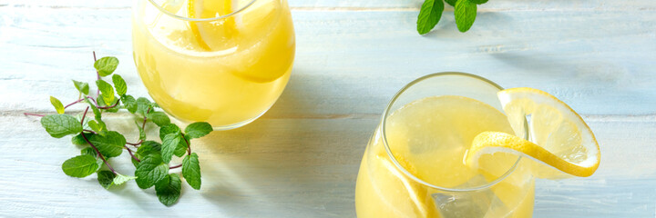 Lemonade panorama on a wooden background. Homemade fresh drink with lemon and mint. Healthy organic...