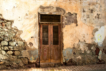 Old wooden door in antique stone building at sunlight. Reconstruction and conservation concept.