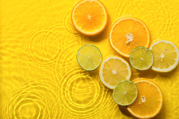 Citrus fruits in yellow water background with concentric circles and ripples. Refreshing summer concept, Copy space