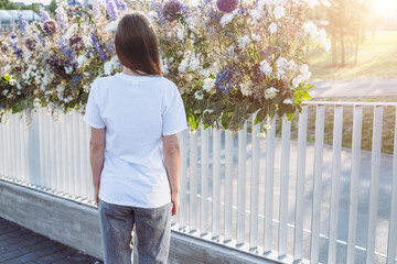 Portrait of young women who wears white T-shirt and posing against a background, back view.