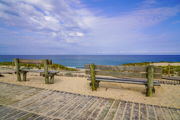 two empty wooden bench on pathway access sandy beach in cap ferret atlantic coast in france