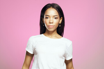 Fototapeta premium joyful woman of african appearance in white t-shirt long hair pink background