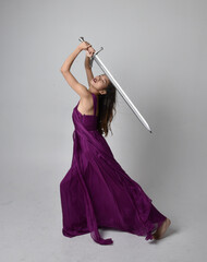 Full length  portrait of pretty brunette asian girl wearing purple flowing  gown. Sitting pose...