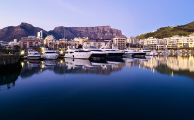 Table Mountain is reflected in the still waters of a marina for luxury motor yachts in Cape Town, South Africa.