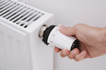Heat radiator knob. Woman hand adjusting temperature on heating radiator