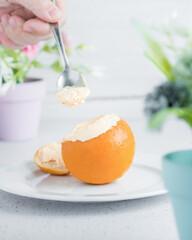 Hand taking some orange ice cream in real frozen orange with white background