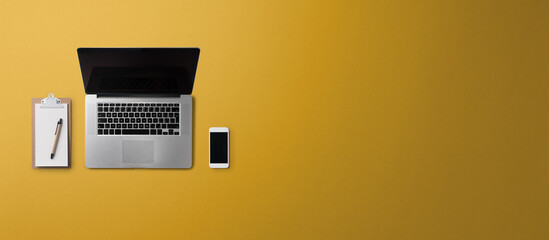 Flat lay top view office desk working space with laptop on yellow background. Copy space.