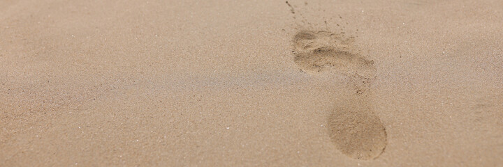 Closeup of footprints from bare feet on sand
