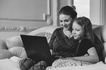 Mom and daughter spend time together with laptop at home