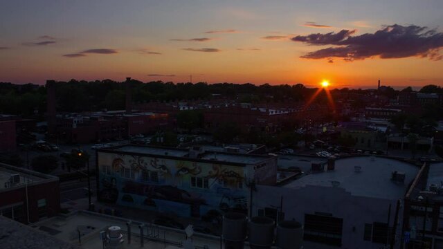 Glorious Sunset Over The City Of Durham In North Carolina With View Of Two Way Bridges (Puentes de Doble Via) Mural On Exterior Wall Of A Building. aerial, time lapse