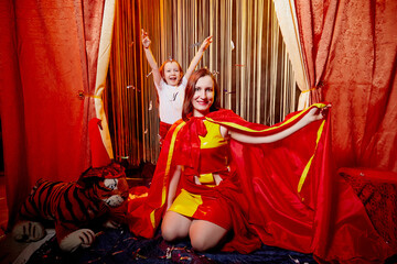 Family during a stylized theatrical circus photo shoot in a beautiful red location. Models mother...