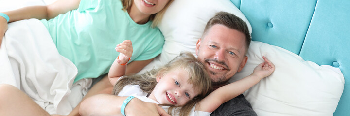 Young man and woman lying with little girl in bed