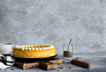 Delicate cheesecake with pumpkin on a wooden board on a concrete background.
