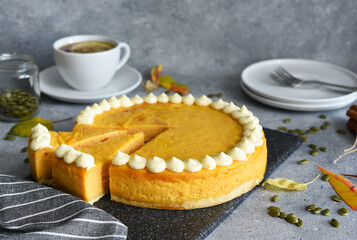 Delicate cheesecake with pumpkin on a wooden board on a concrete background.